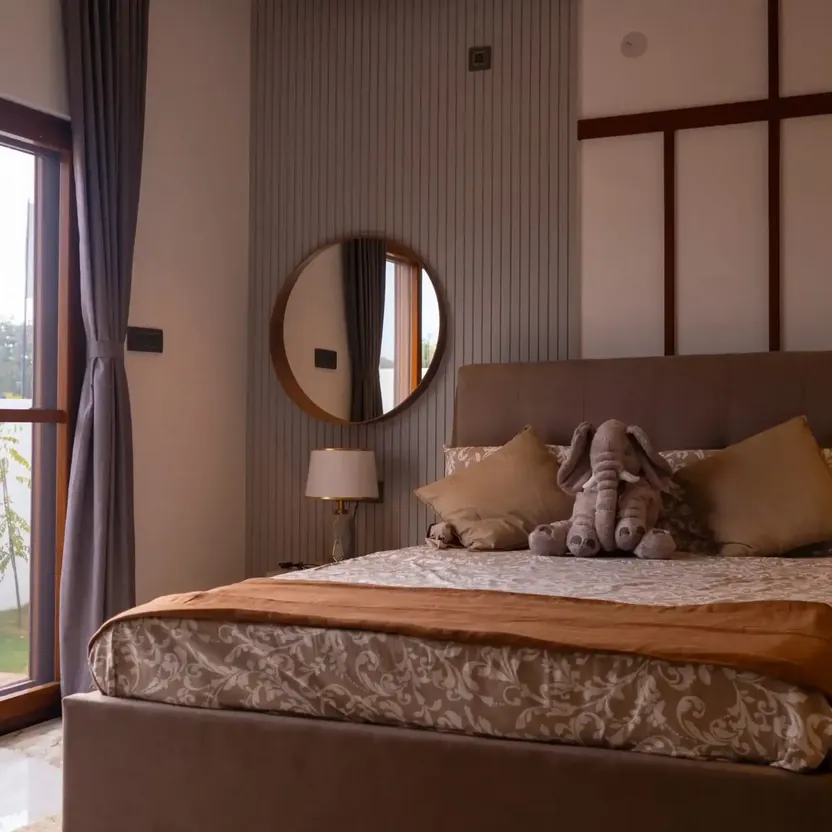 Elegance by Guru Punvaanii, Bidadi, show villa A bedroom with a padded headboard, a round mirror and a balcony door in the Elegance show villa