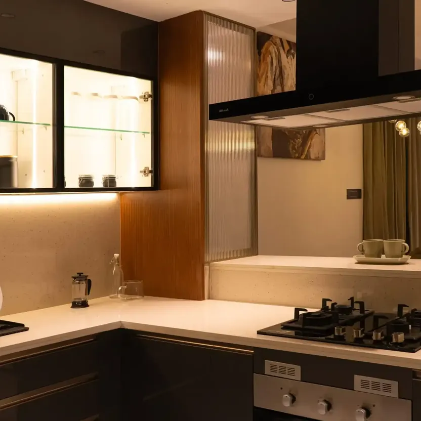 Elegance by Guru Punvaanii, Bidadi, show villa A kitchen with a hob, a chimney hood and lit glass cabinets in the Elegance show villa